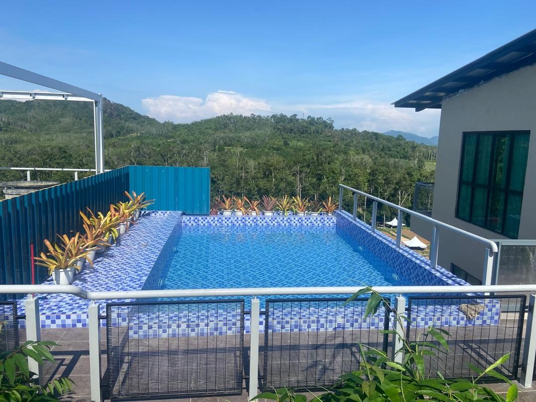 Kolam infiniti bermozek biru dengan pasu bromeliad, menghadap bukit berhutan