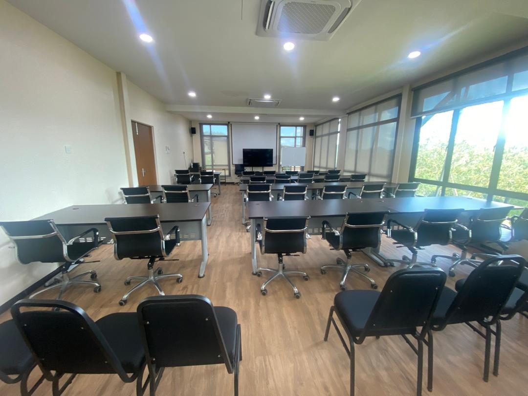 Bilik seminar kosong disusun bentuk U dengan kerusi eksekutif dan skrin projektor